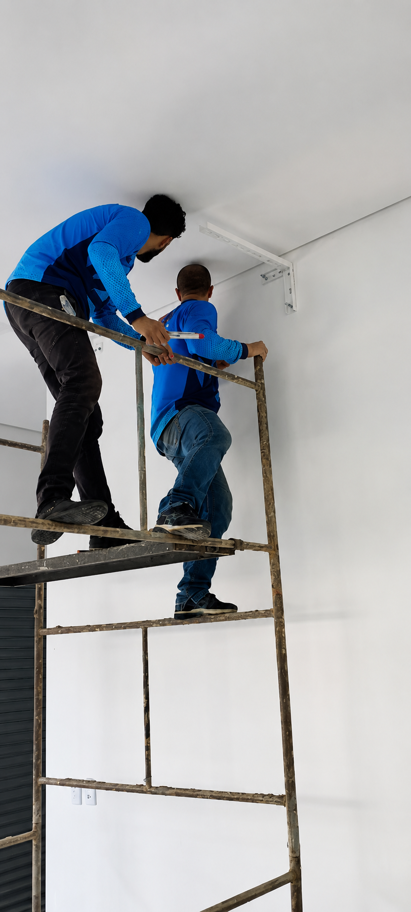 Equipe IGS instalando suporte de ar condicionado em altura